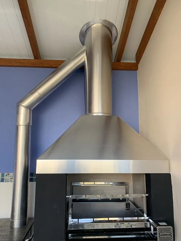 Coifa de inox sobre churrasqueira com paredes azuis